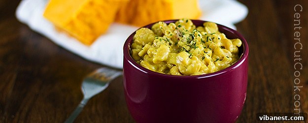 A bowl of irresistibly creamy mac and cheese, topped with fresh herbs.