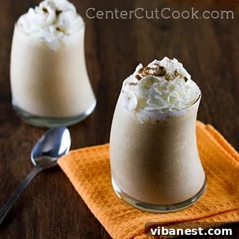 Pumpkin Pie Smoothie with Whipped Cream Garnish Closeup view of a single glass of Pumpkin Pie Smoothie, garnished with whipped cream and cinnamon, ready to be enjoyed as a delightful autumn drink.