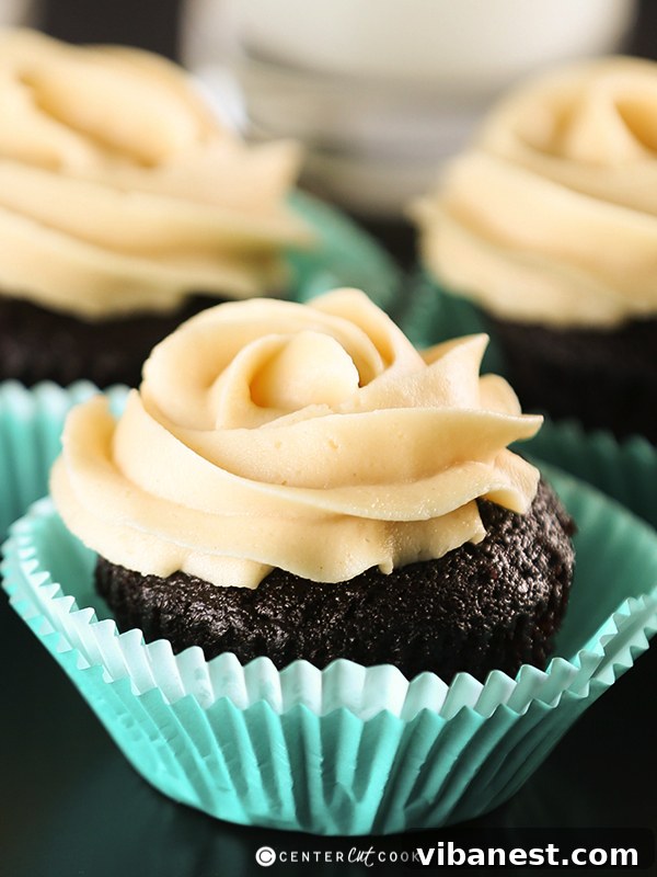 chocolate peanut butter cupcakes 4 A batch of freshly baked chocolate peanut butter cupcakes, some already frosted with a generous swirl.