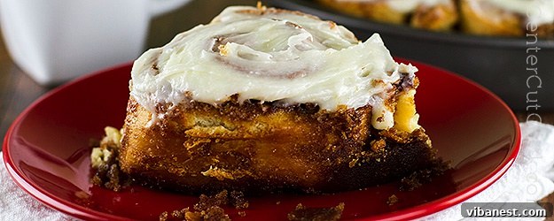 Delicious, warm cinnamon rolls with generous cream cheese frosting on a serving plate, ready to be enjoyed.