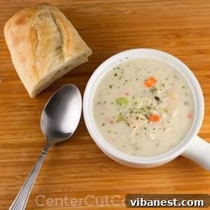 A bowl of Slow Cooker Cream of Chicken & Wild Rice Soup with a spoon and crusty bread.