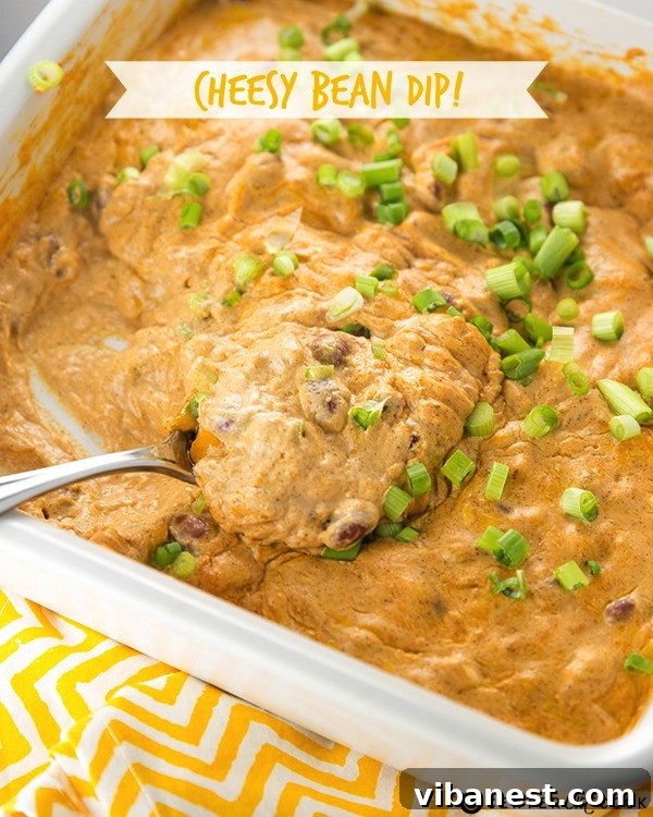Irresistible Cheesy Bean Dip Close-up of bubbling cheesy bean dip with golden tortilla chips on the side, ready to be scooped