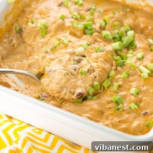 Baking dish of Cheesy Bean Dip, golden brown and bubbly from the oven, with a side of tortilla chips