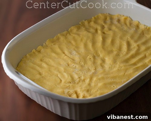 The golden brown base of the Chess Cake crust, expertly pressed into a 9x13 inch baking dish, showcasing its perfect texture and readiness for the creamy topping.