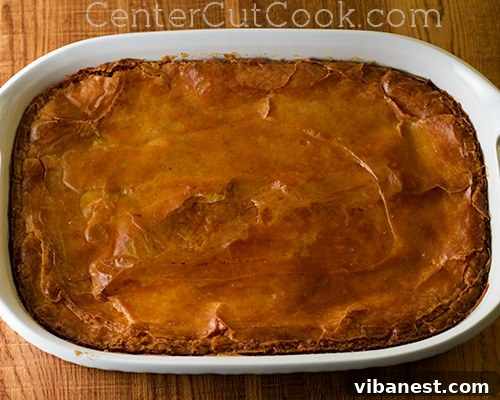 The Chess Cake, freshly out of the oven, golden brown and perfectly baked, showing a slightly flaky top and creamy interior, cooling on a wire rack.