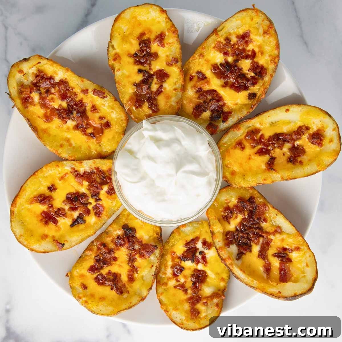 Fully Loaded Potato Boats 12 A finished platter of loaded potato skins, each adorned with a swirl of sour cream and a sprinkle of green onions, ready for enjoyment.