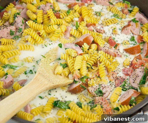 Sizzling Skillet Sausage Delight 6 Pasta simmering with sausage, tomatoes, and spinach in a creamy sauce