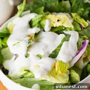 Homemade ranch dressing in a clear glass jar, garnished with fresh dill and chives
