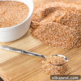 A small bowl of flavorful dry rub seasoning with a spoon, perfect for ribs, chicken, and other grilled meats.