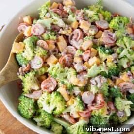 Bowl of easy broccoli salad with bacon, cheddar cheese, tomatoes and onion.