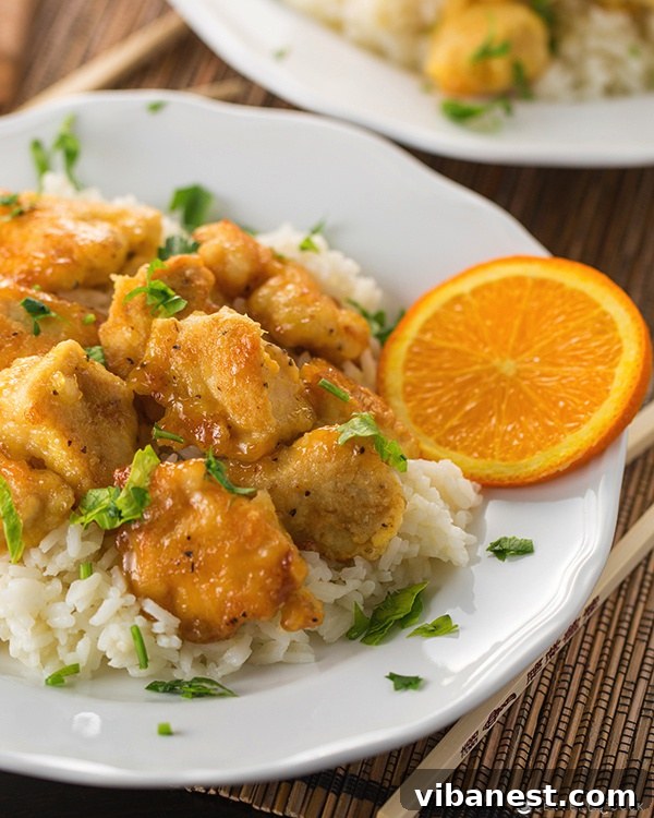 Close-up of crispy Orange Chicken pieces coated in a vibrant sauce