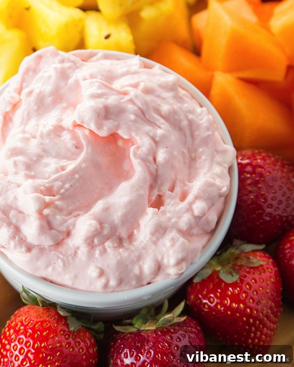 Sweet Cream Cheese Fruit Dip with Fresh Berries Close-up of the smooth, light pink fruit dip in a decorative bowl, surrounded by vibrant fresh strawberries, blueberries, and green grapes