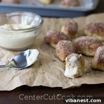 A close-up of fluffy homemade cinnamon sugar pretzel bites with a dollop of creamy cream cheese dip.