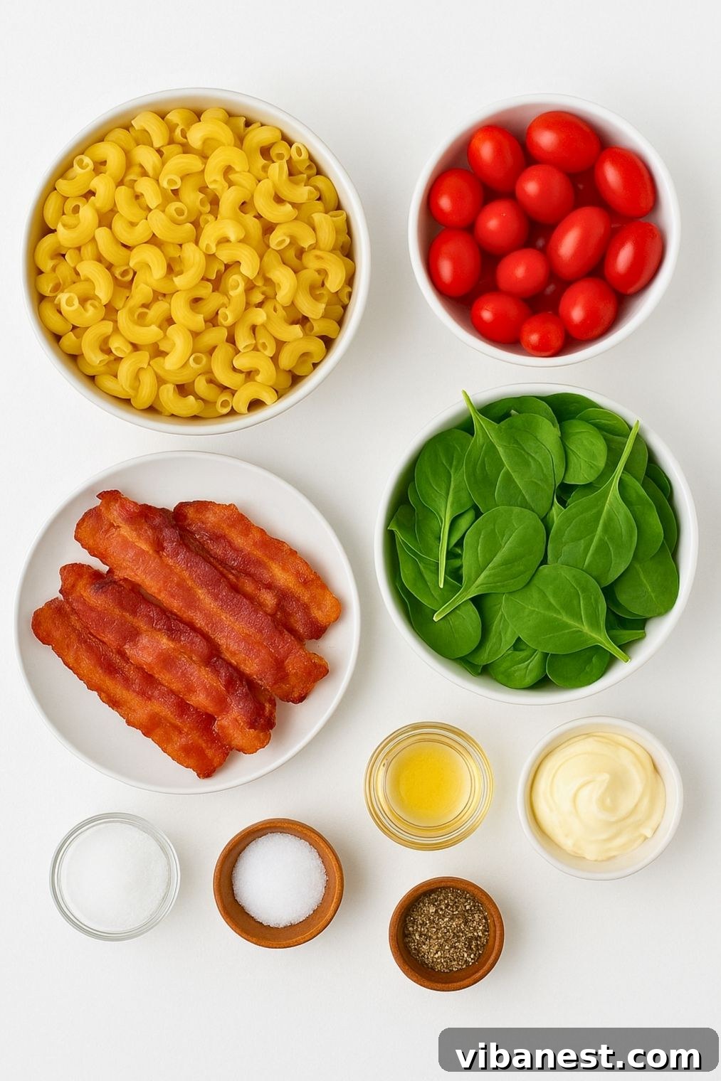 Smoky BLT Pasta Salad 4 Various ingredients laid out for BLT pasta salad preparation, including cooked pasta, bacon, tomatoes, spinach, and dressing components.