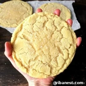 A large, perfectly round jumbo sugar cookie, featuring a light golden hue and a smooth texture.